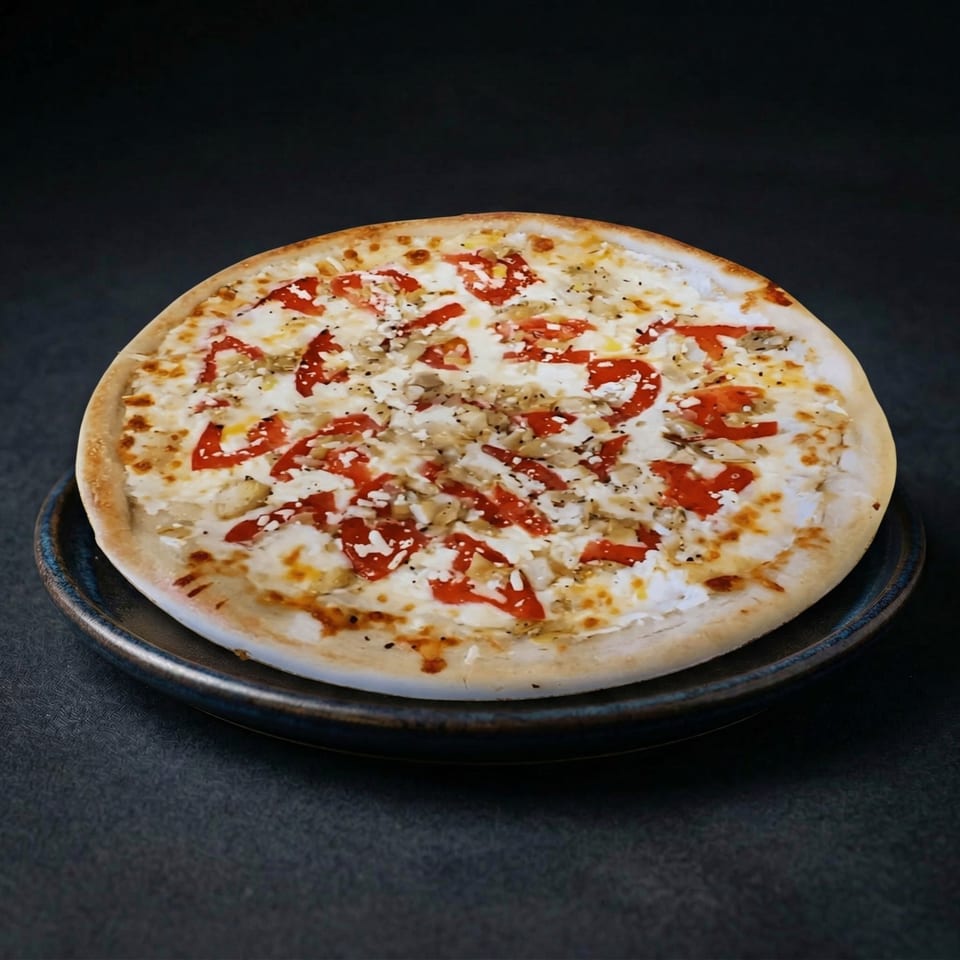 Pat's Place Greek pizza with white sauce, red tomatoes, and feta cheese on a dark plate.